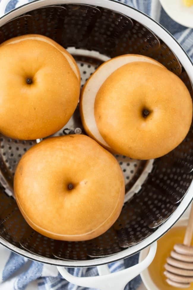 A white pot of three steamed asian apple pears.