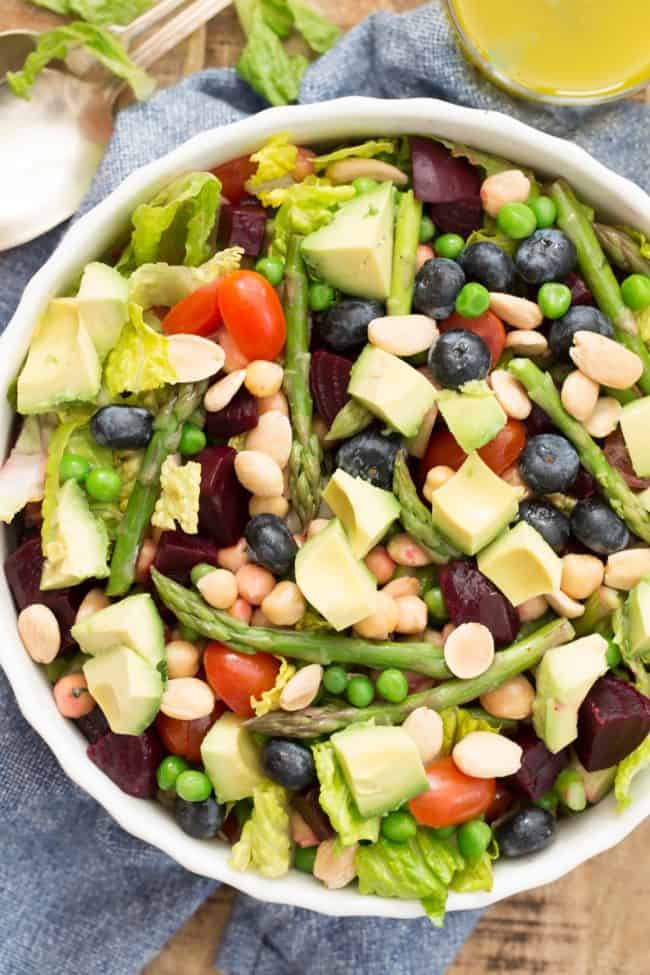 white bowl of salad tossed with blueberries and avocado