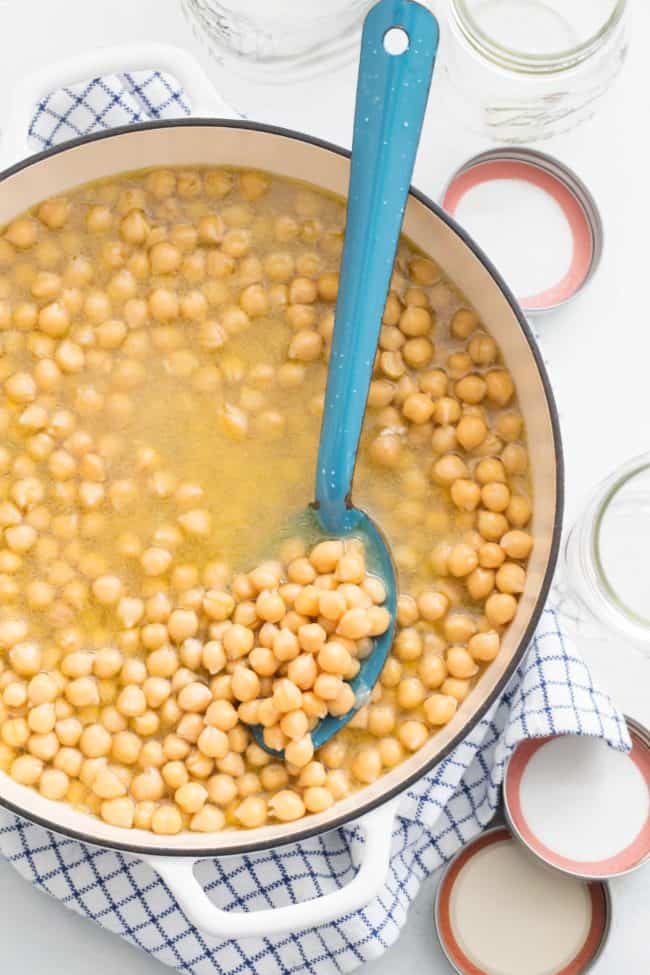 A white pot filled with cooked legumes.