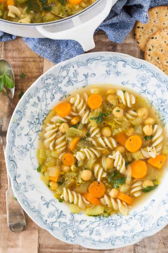 A blue and white bowl filled with chickpea noodle soup.