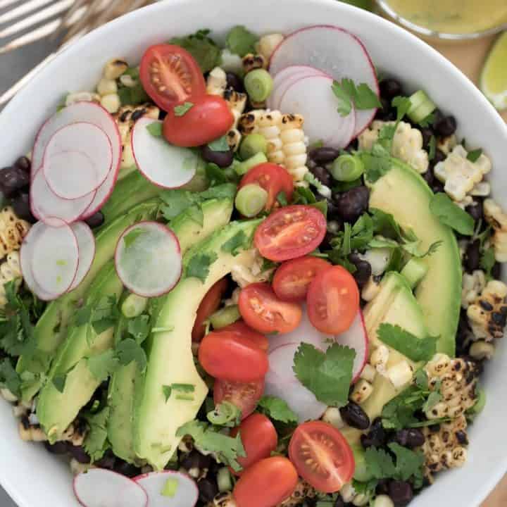 Black bean and corn salad is a mix of black beans, grilled corn, cherry tomatoes, radishes, parsley, scallions and avocado all tossed in a perky dressing