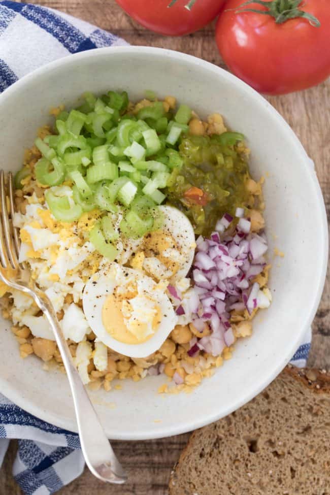 A white bowl filled with chopped celery, onion, relish and chickpeas.