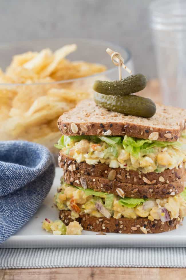 A chickpea egg salad sandwich on a white plate.