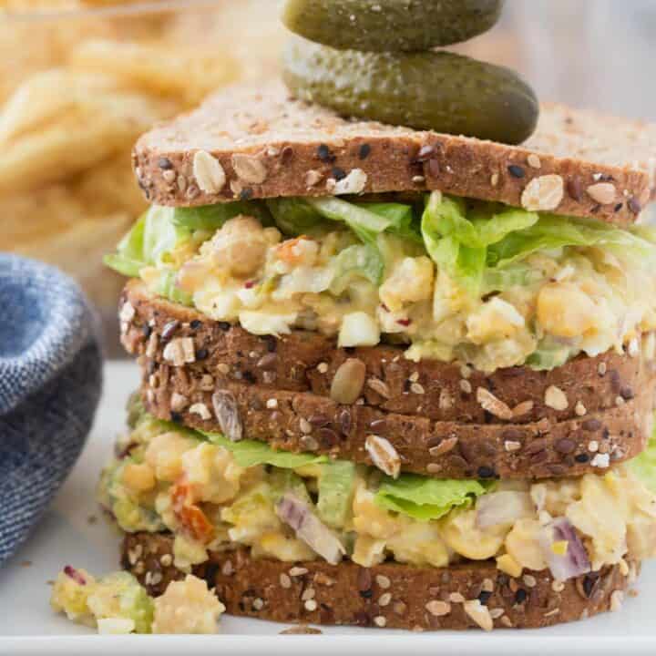 A chickpea egg salad sandwich on a white plate.