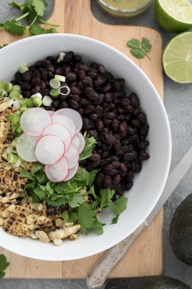 A white bowl filled with legumes and vegetables.
