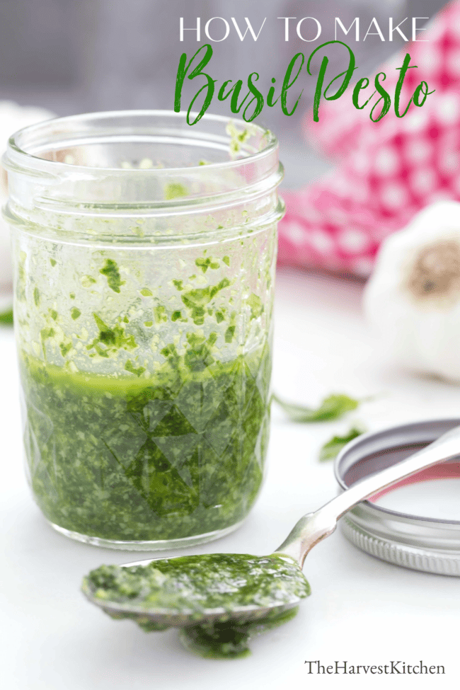 A clear glass jar filled with homemade basil pesto sauce.