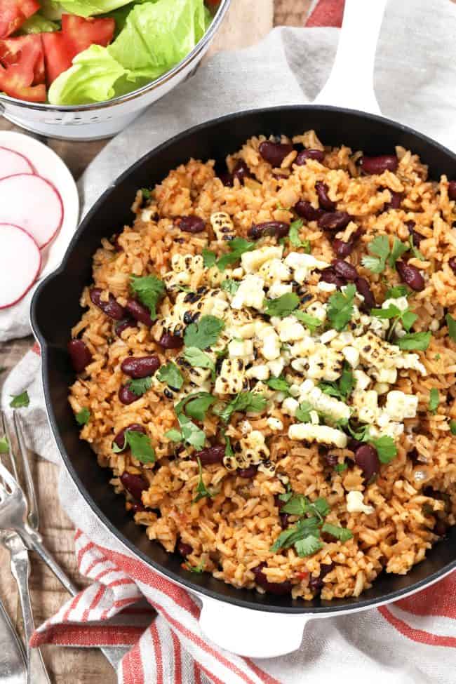 A skillet of Spanish rice and beans with grilled corn.