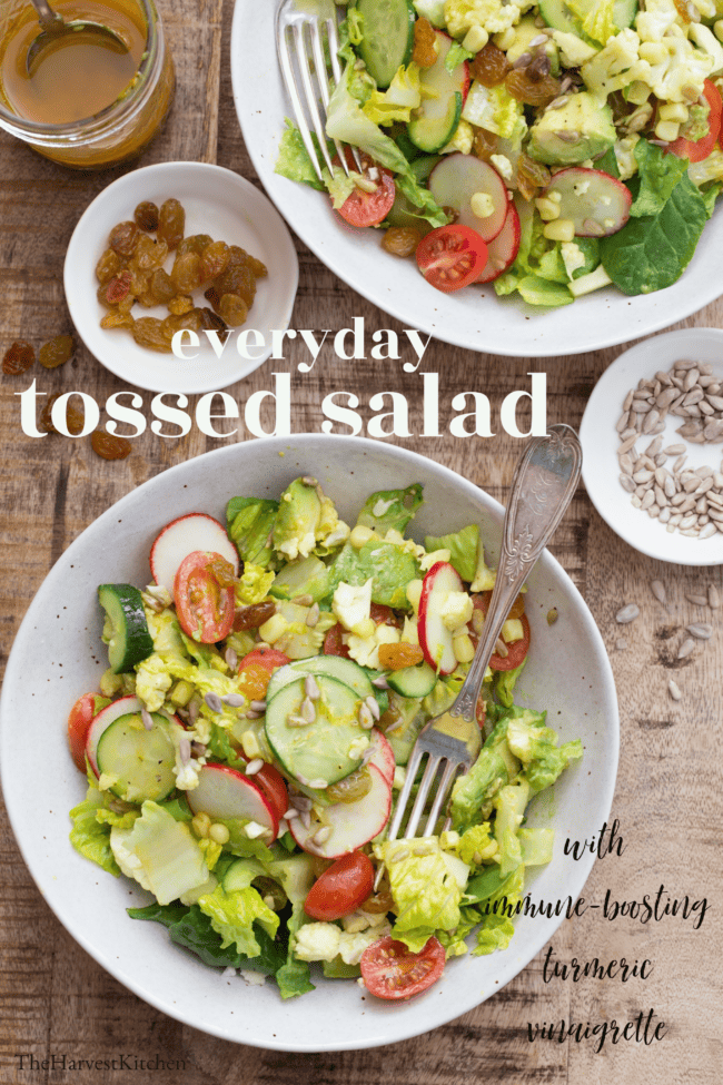 Two white bowls filled with tossed salad. A fork rests in both bowls.