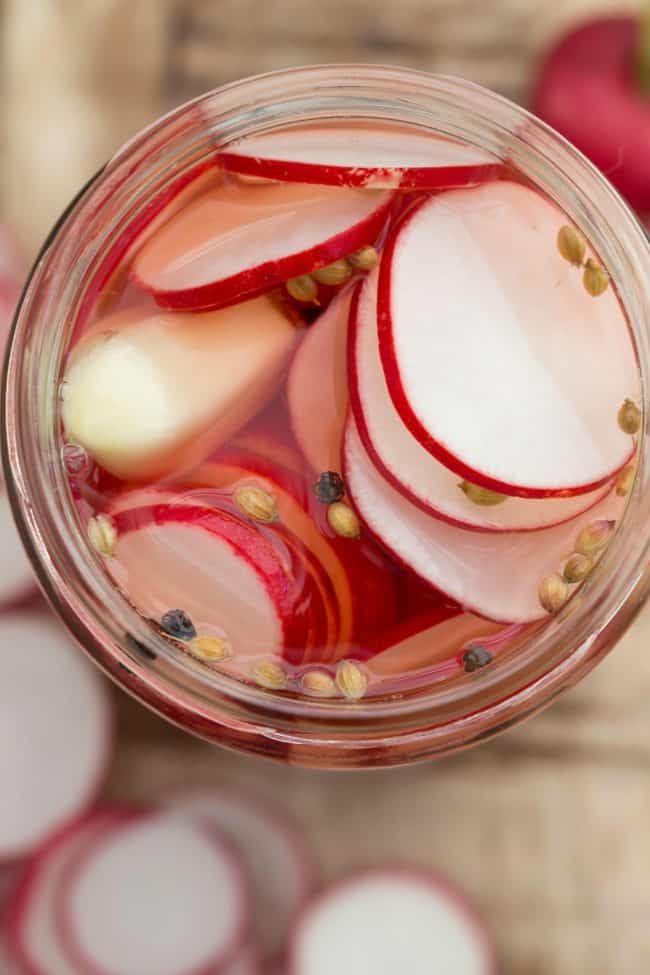 A clear glass mason jar filled with pickled radishes.