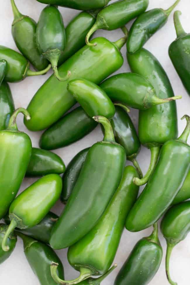 Several green peppers scattered on a counter.