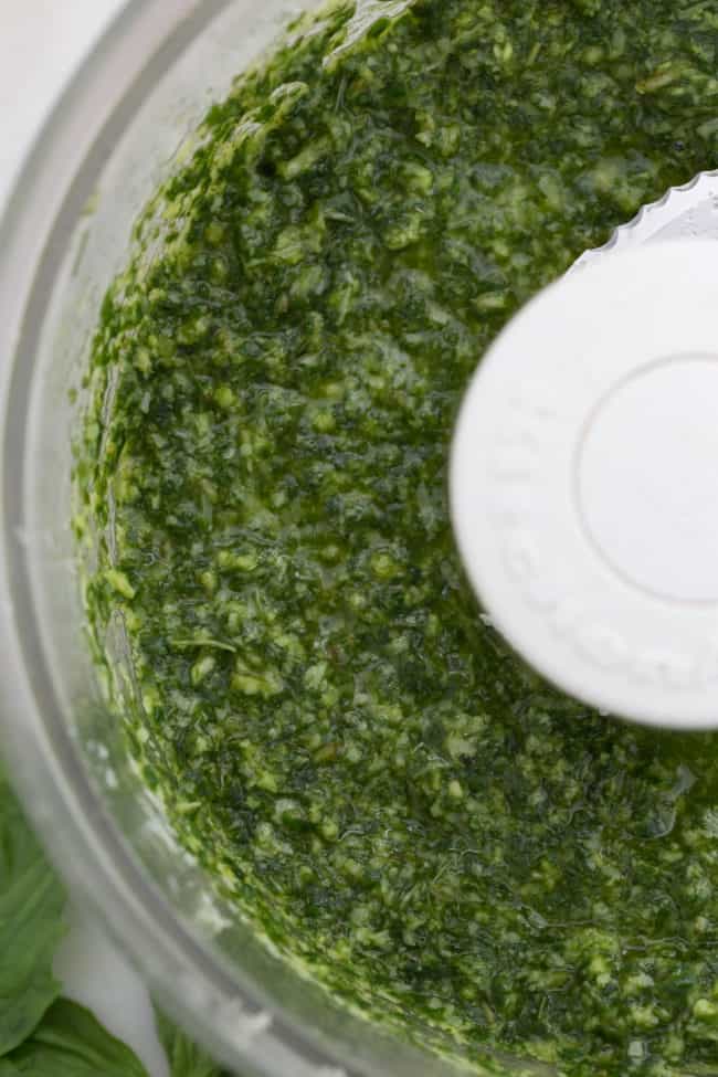A food processor filled with green sauce.