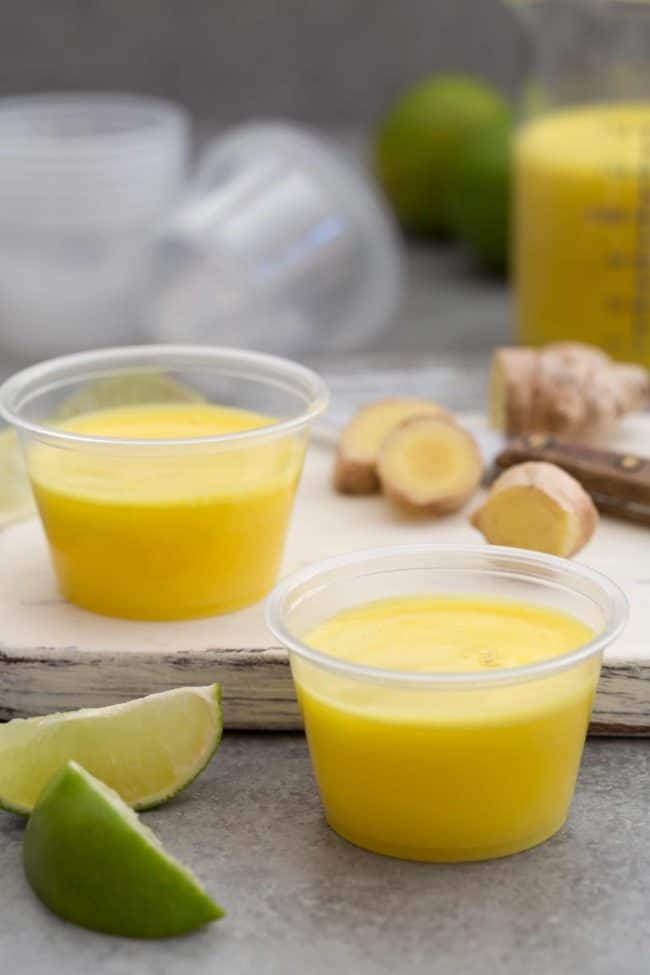 Small plastic containers filled with pineapple ginger shots (juiced pineapple and ginger recipe).