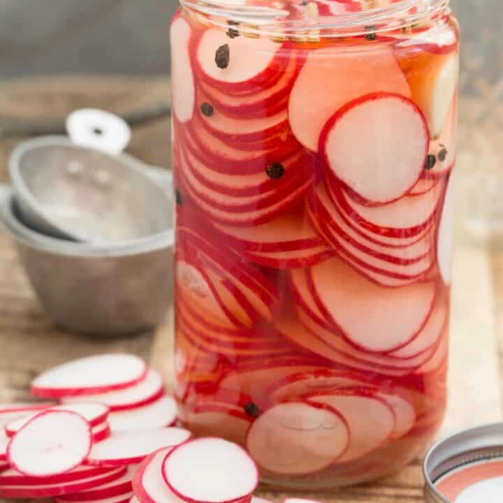 jA mason jar filled with quick pickled radishes.