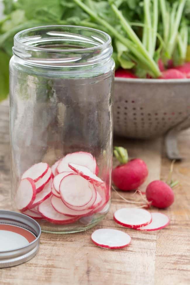 A clear glass mason jar with sliced vegetables.