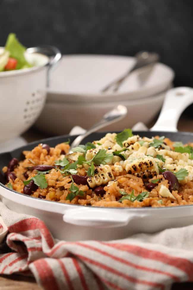 A skillet of Spanish rice and beans with grilled corn.