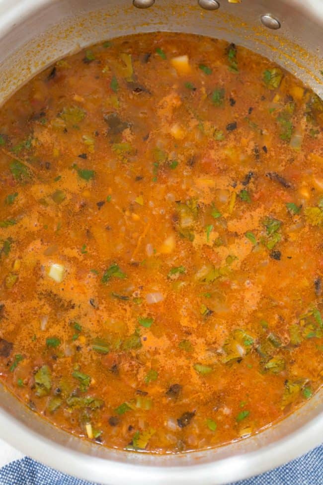 A pot of simmering rice in tomato broth.
