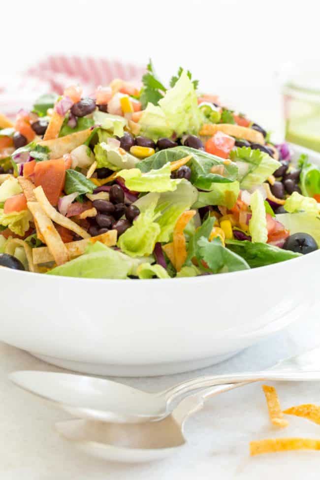 white bowl filled with chopped Mexican chopped. Two serving spoons sit in front of the bowl.