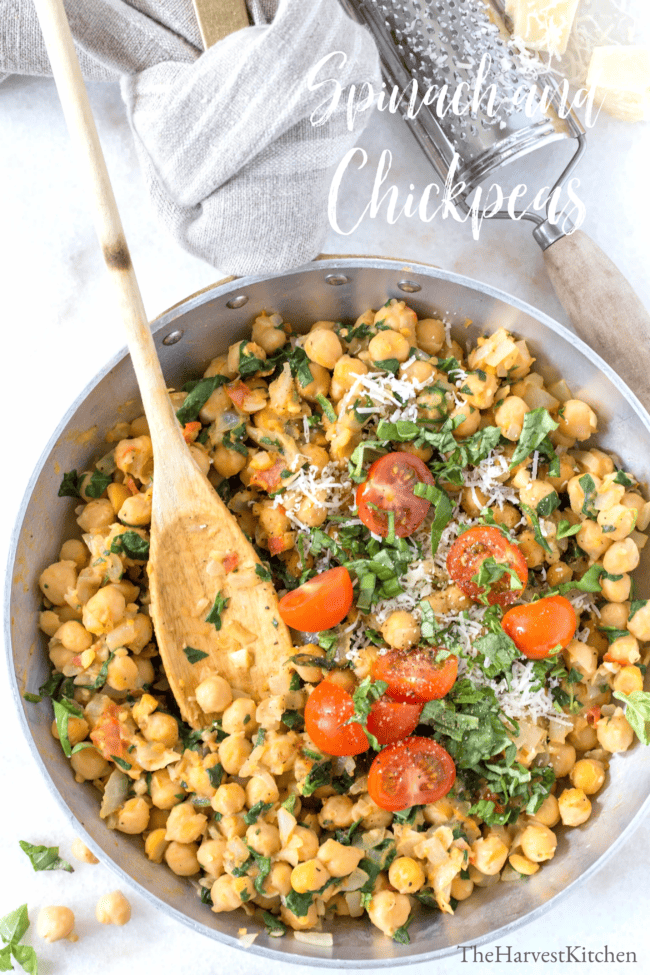 An aluminum skillet filled with cooked chickpeas and spinach. 