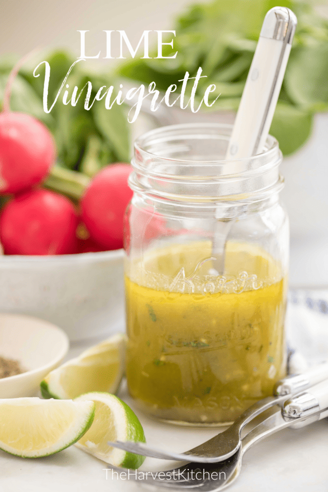 glass mason jar half filled with homemade salad dressing. Colander in the back with lettuce.