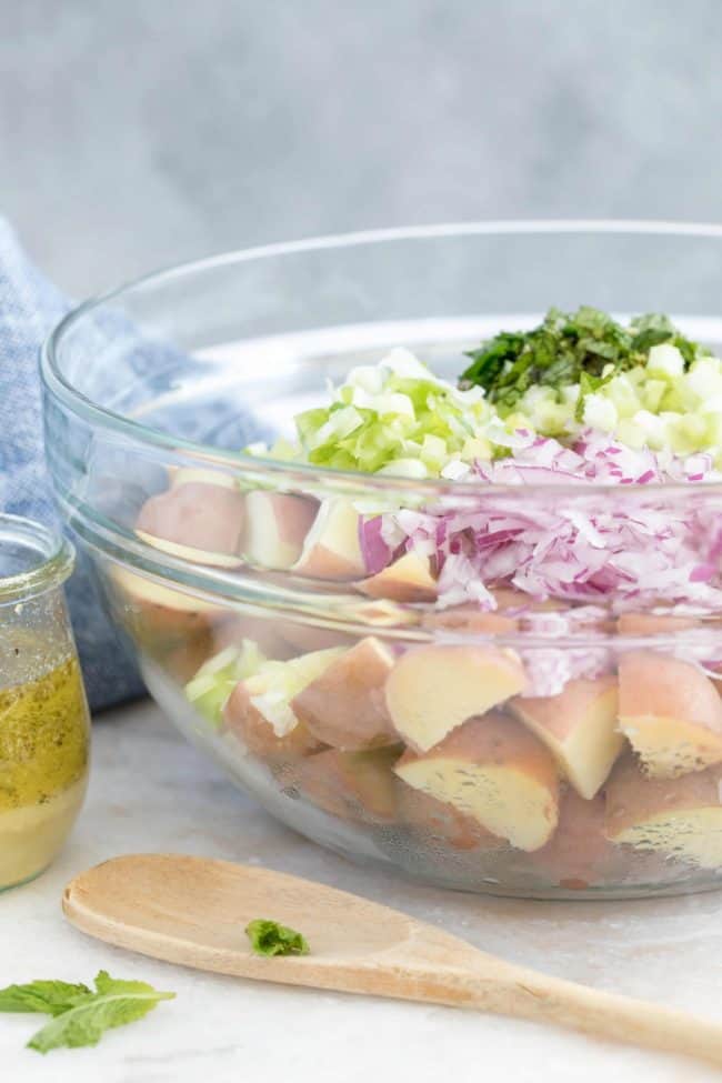 A clear mixing bowl filled with chopped vegetables.