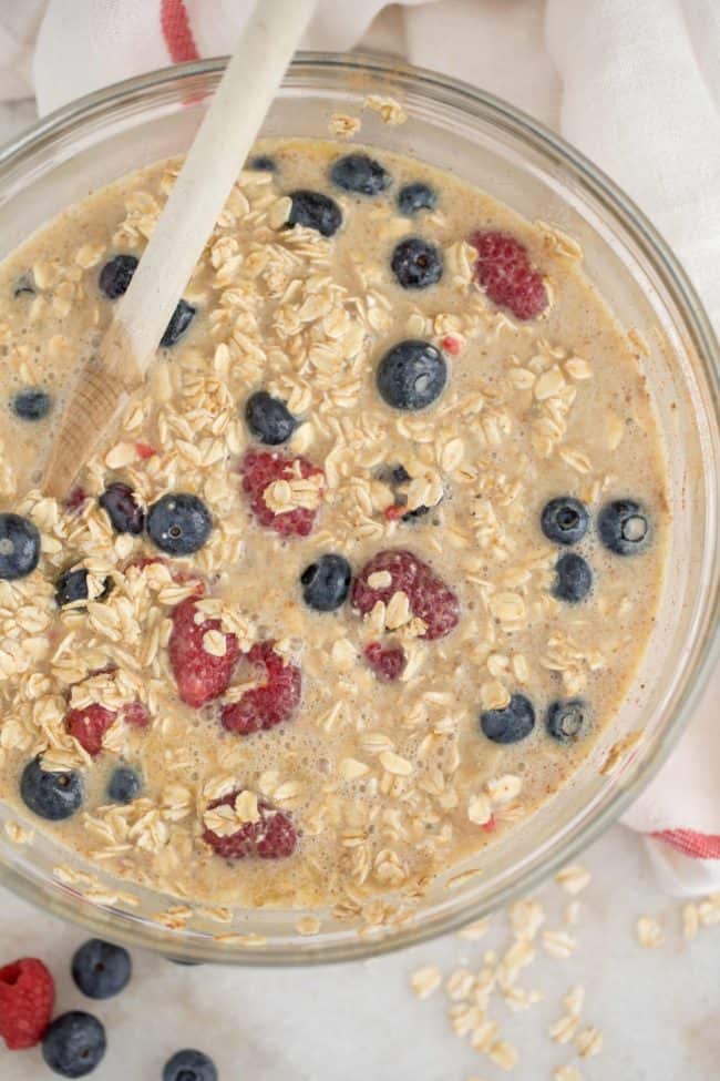 A clear mixing bowl filled with banana berry baked oatmeal batter.