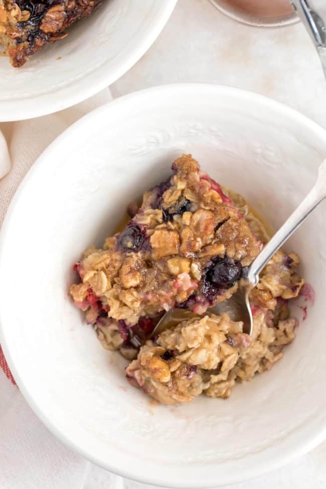 A white plate with piece of berry baked oatmeal on it.