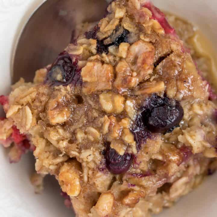 A white bowl with a serving of baked oatmeal in it. A spoon rests in the bowl.