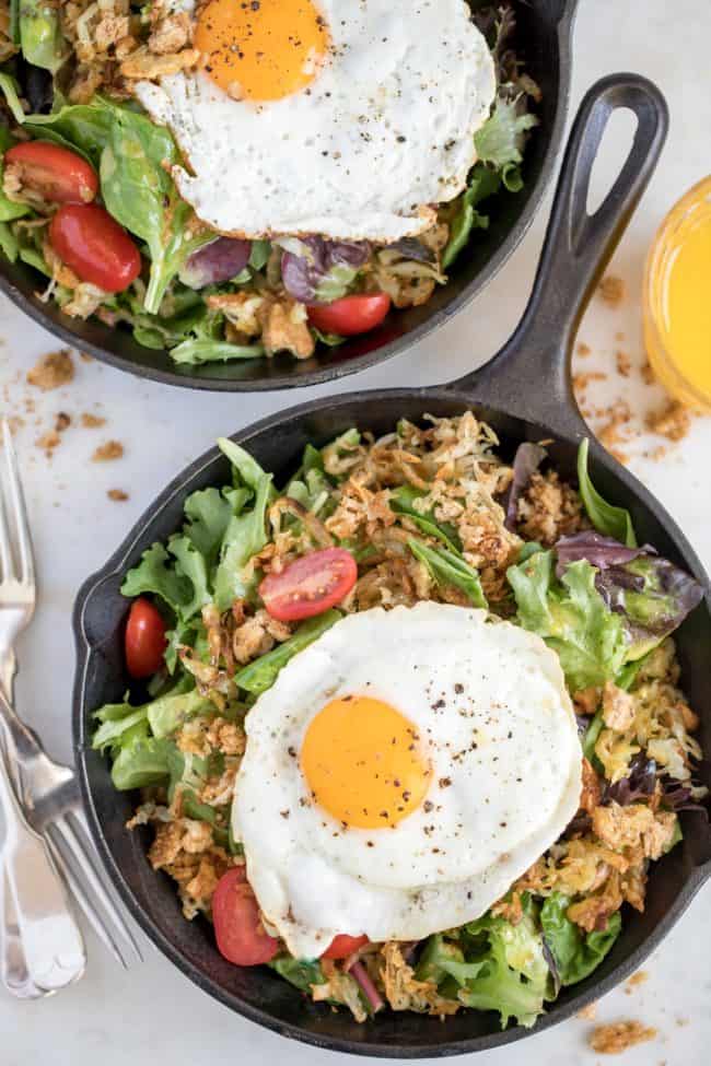 pans filled with salad greens and fried eggs