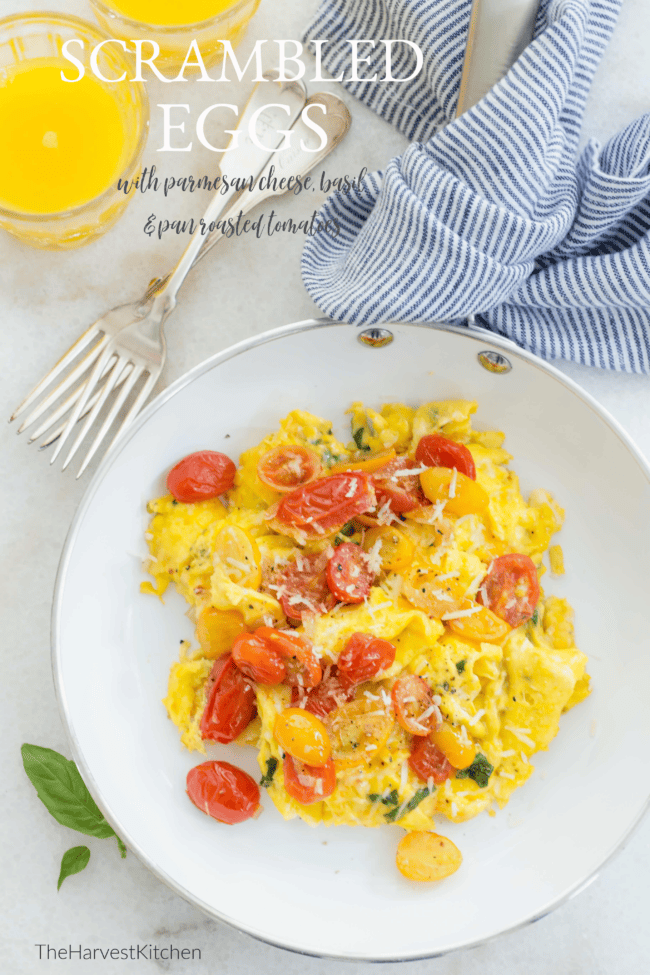 A white skillet filled with scrambled eggs with tomatoes.