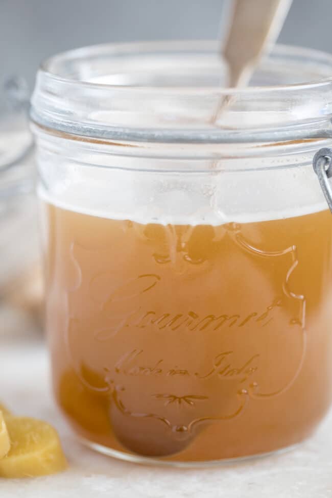 A clear glass jar of ginger syrup