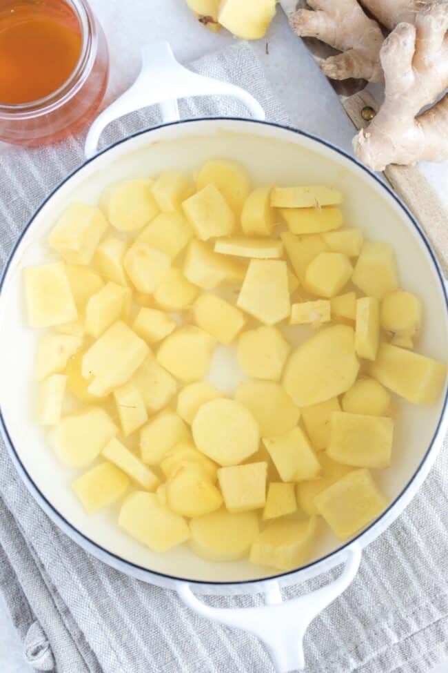 A white pot of spice root simmering in water.