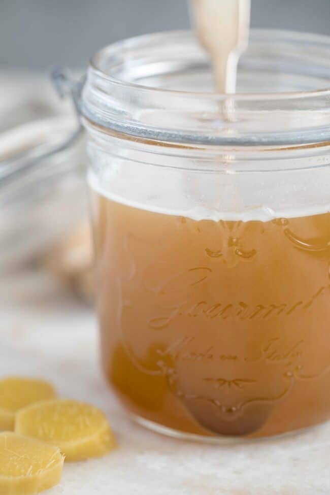 A clear glass mason jar filled with ginger juice.