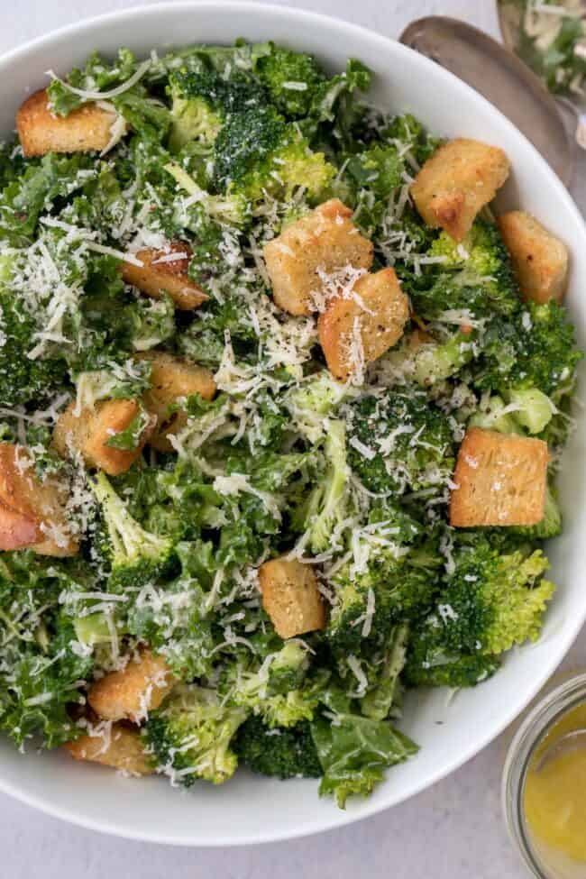 A white salad bowl filled with broccoli kale salad with croutons.