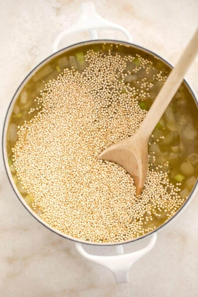 pan with sauteed onion, garlic and quinoa simmering in vegetable broth