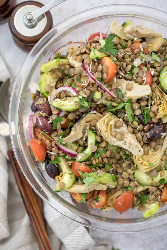 A glass bowl filled with Mediterranean lentil salad.