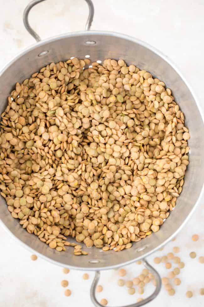 A metal colander filled with rinsed dried legumes.