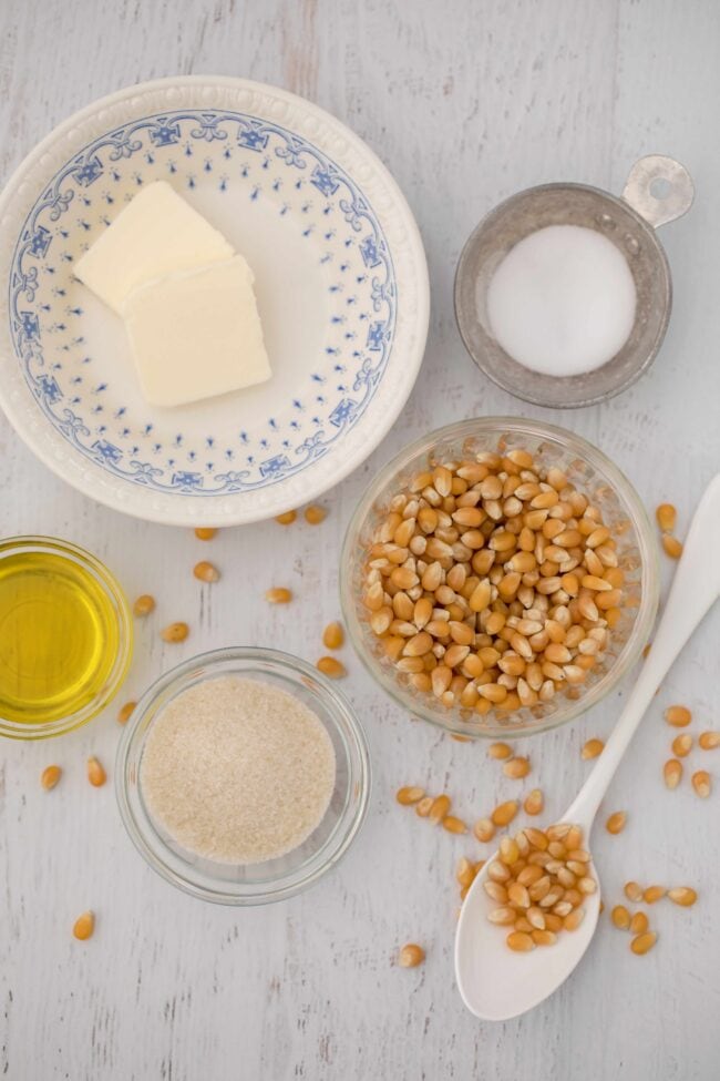 Clear glass bowls filled with popcorn kernels, oil and butter - ingredients for homemade kettle corn.