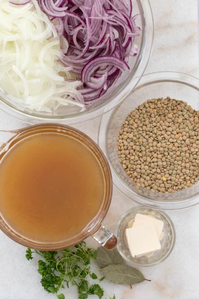 Clear glass bowls filled with sliced onions, legumes, broth and butter.