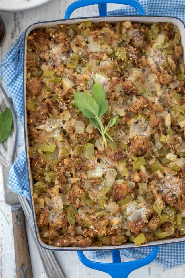 Blue baking dish filled with bread stuffing. A spatula sits next to the dish.