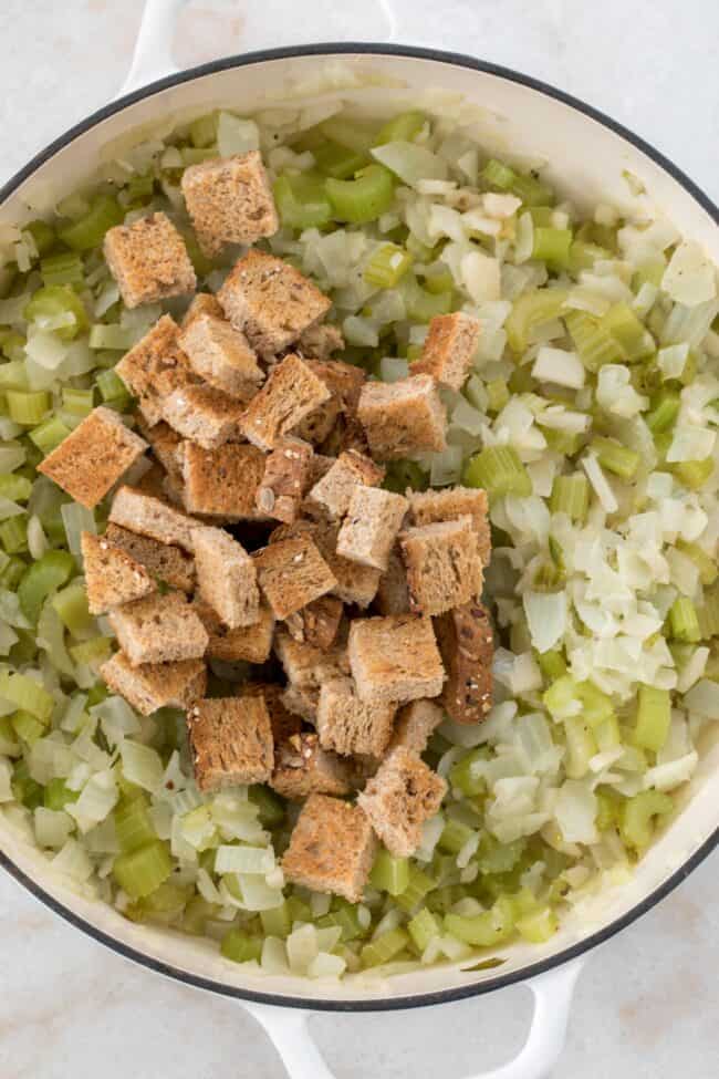 White pan with sauteed onions and celery and toasted bread cubes