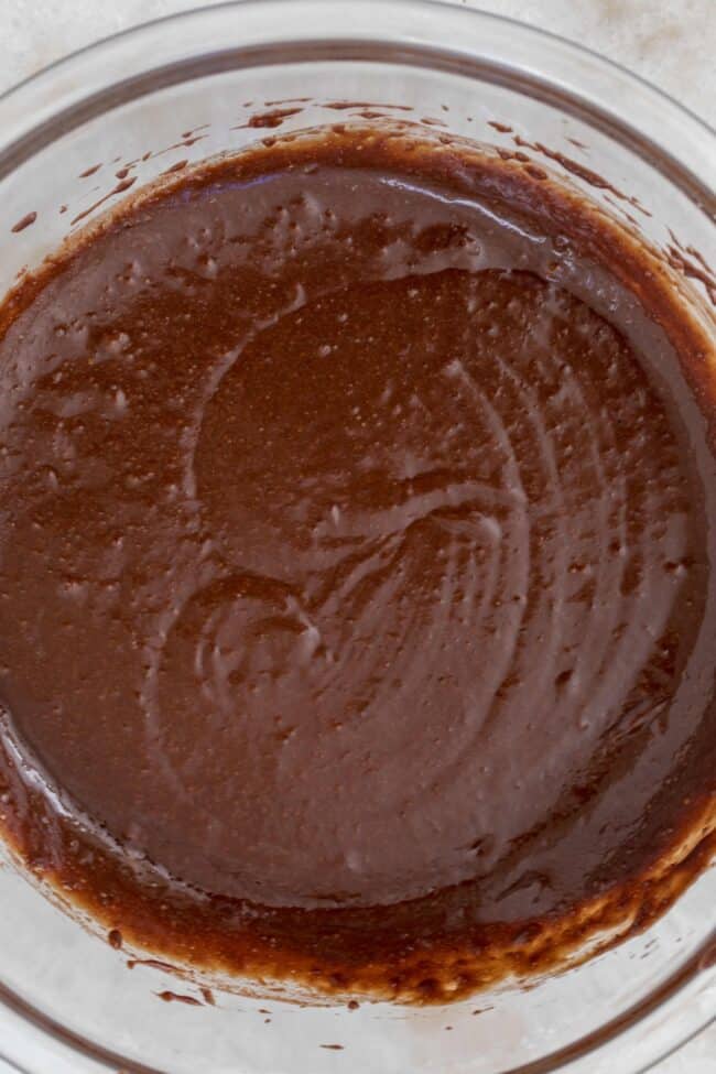A clear glass mixing bowl filled with chocolate batter.