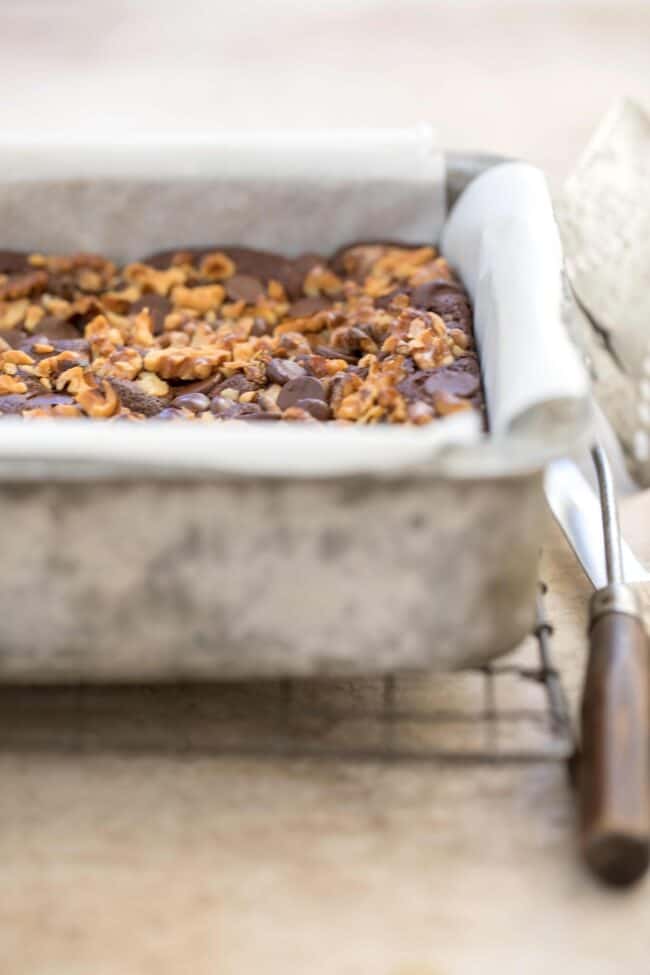 A baking pan filled with almond flour brownies. A spatula sits next to the pan.