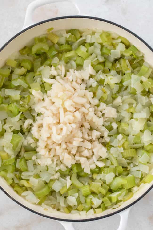 White pan with sauteed onions and celery for a vegan stuffing recipe