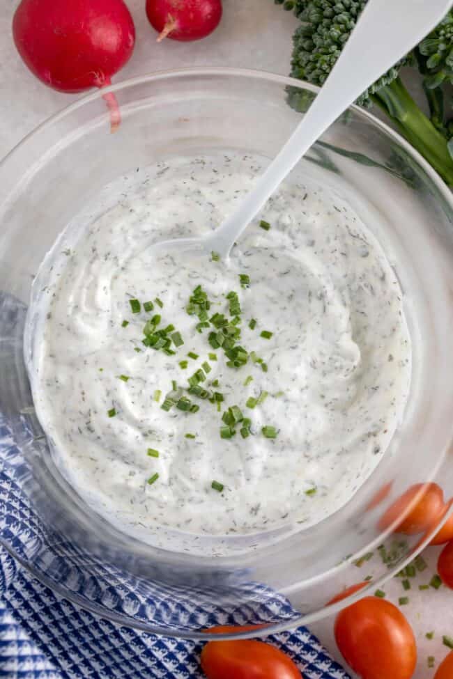 A clear glass mixing bowl filled with homemade ranch dip.