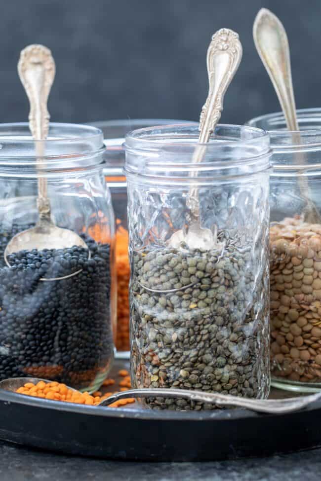 Several clear jars of dried lentils.
