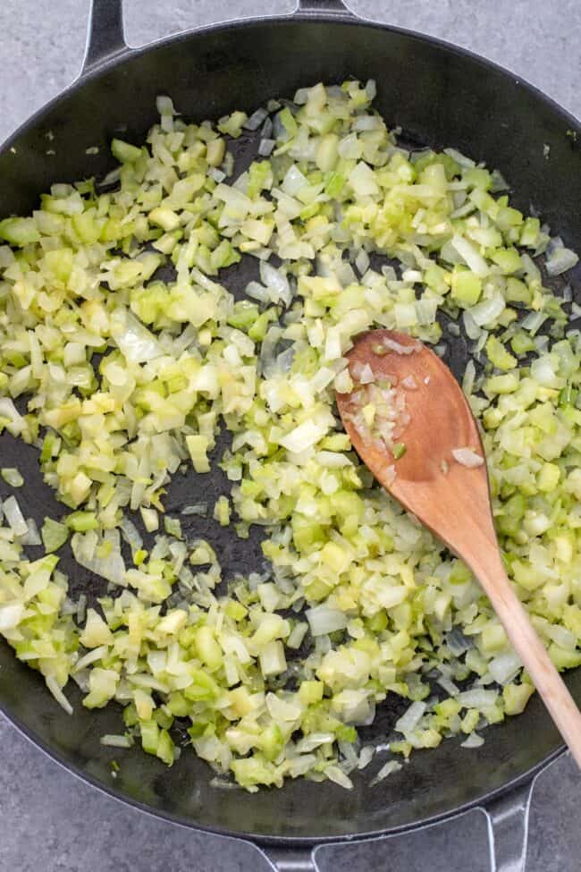 A skillet filled with cooked chopped onion and celery.