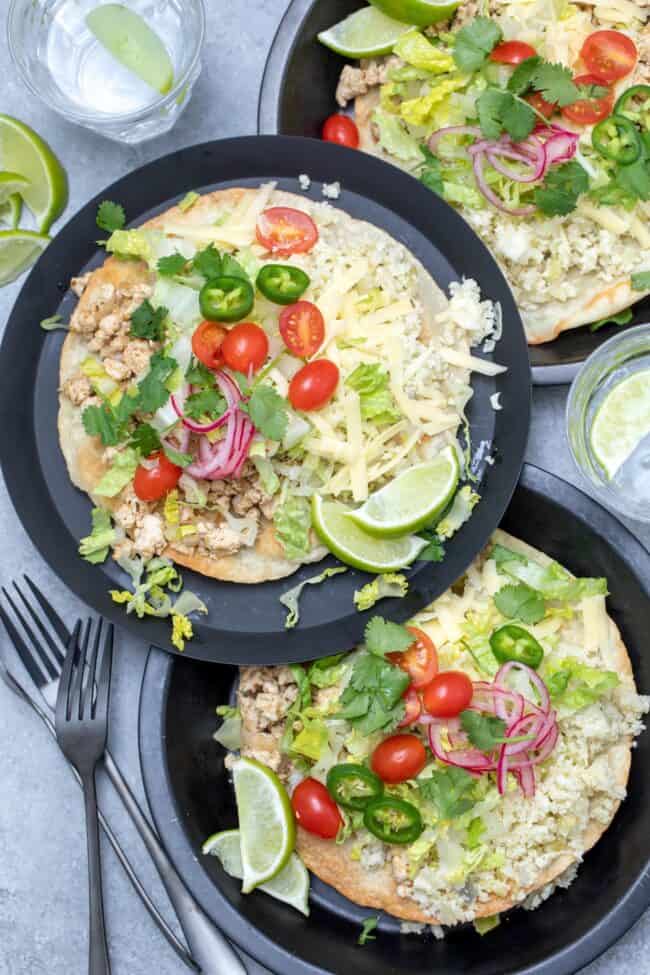 Three plates with Mexican four tortillas topped with ground meat, cheese, onions and tomatoes.