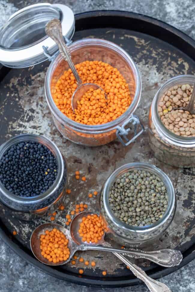 Several clear jars with different types of lentils in them.