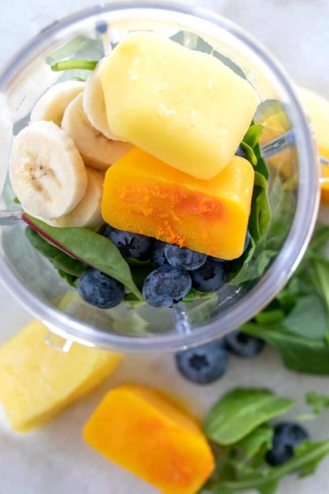 Fruit ice cubes (smoothie cubes) in a clear plastic blender container.