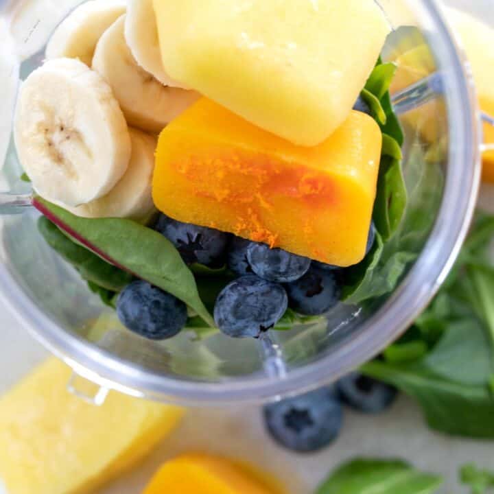 A blender container filled with frozen smoothie cubes (mango cubes an pineapple cubes).